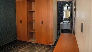 Ein Zimmer mit einem Holzschrank, einem Marmorboden und einem Badezimmer mit Waschbecken und Spiegel.