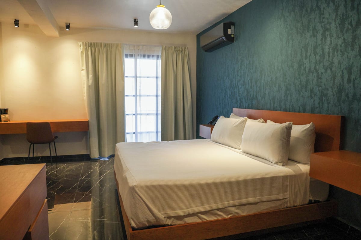 Una camera d'albergo con un letto, una scrivania, una sedia e una finestra con tende.