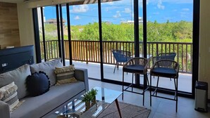 A spacious living room with a large sliding glass door leading to a balcony with outdoor furniture. - BOHO Loft Steps from the Beach (Holbox)