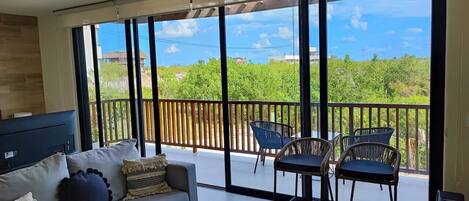 A spacious living room with a large sliding glass door leading to a balcony with outdoor furniture.