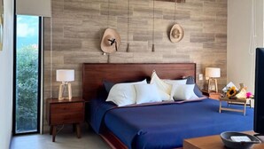 A modern bedroom with a large bed, wooden headboard, and a view of greenery outside. - BOHO Loft Steps from the Beach (Holbox)