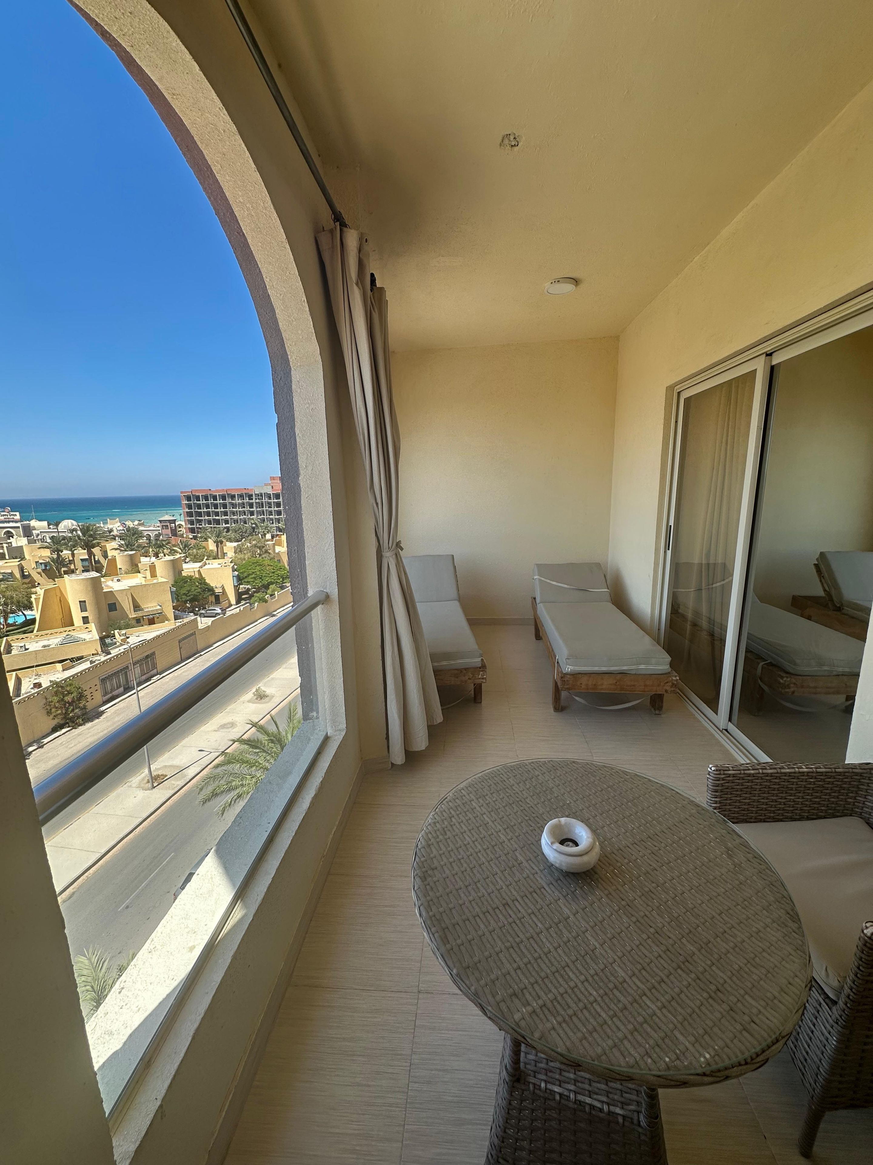 Un balcon avec vue sur la mer, une table et deux fauteuils de relaxation.