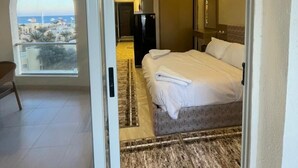 A hotel room with a bed, a view through a glass door, a ceiling with a cloud design, and a small balcony. - Florenza Khamsin Resort (Hurghada)