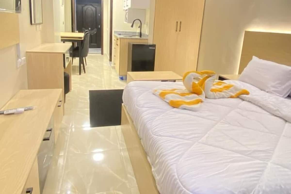 A hotel room with a bed, a desk, a chair, a wardrobe, and a bathroom.