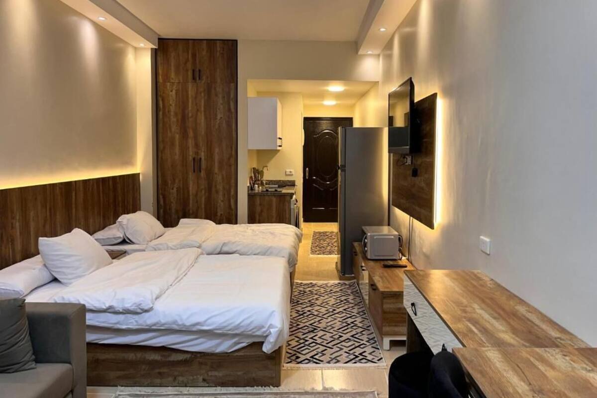 A modern hotel room with a large bed, a desk, and a TV mounted on the wall.