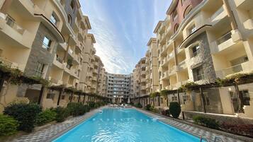 Una piscina rodeada de edificios residenciales de varios pisos con balcones y detalles de piedra.