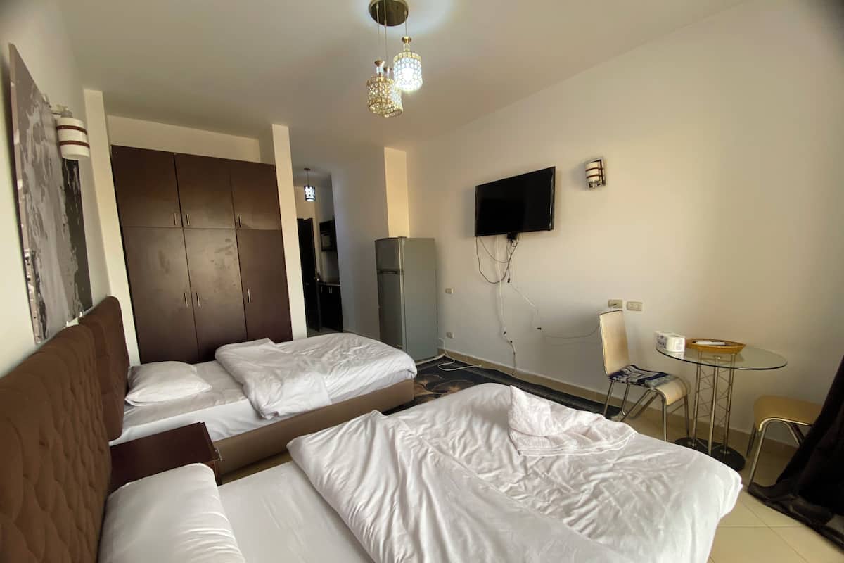 A hotel room with two beds, a TV, a small table, and a chair.