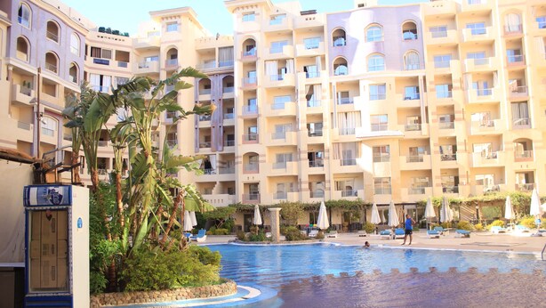 A hotel with a swimming pool, multiple balconies, and outdoor seating areas. - Florenza Khamsin Resort (Hurghada)