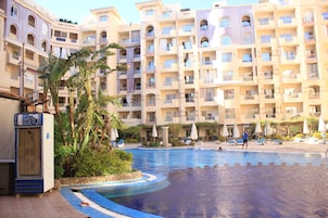 A hotel with a swimming pool, multiple balconies, and outdoor seating areas.