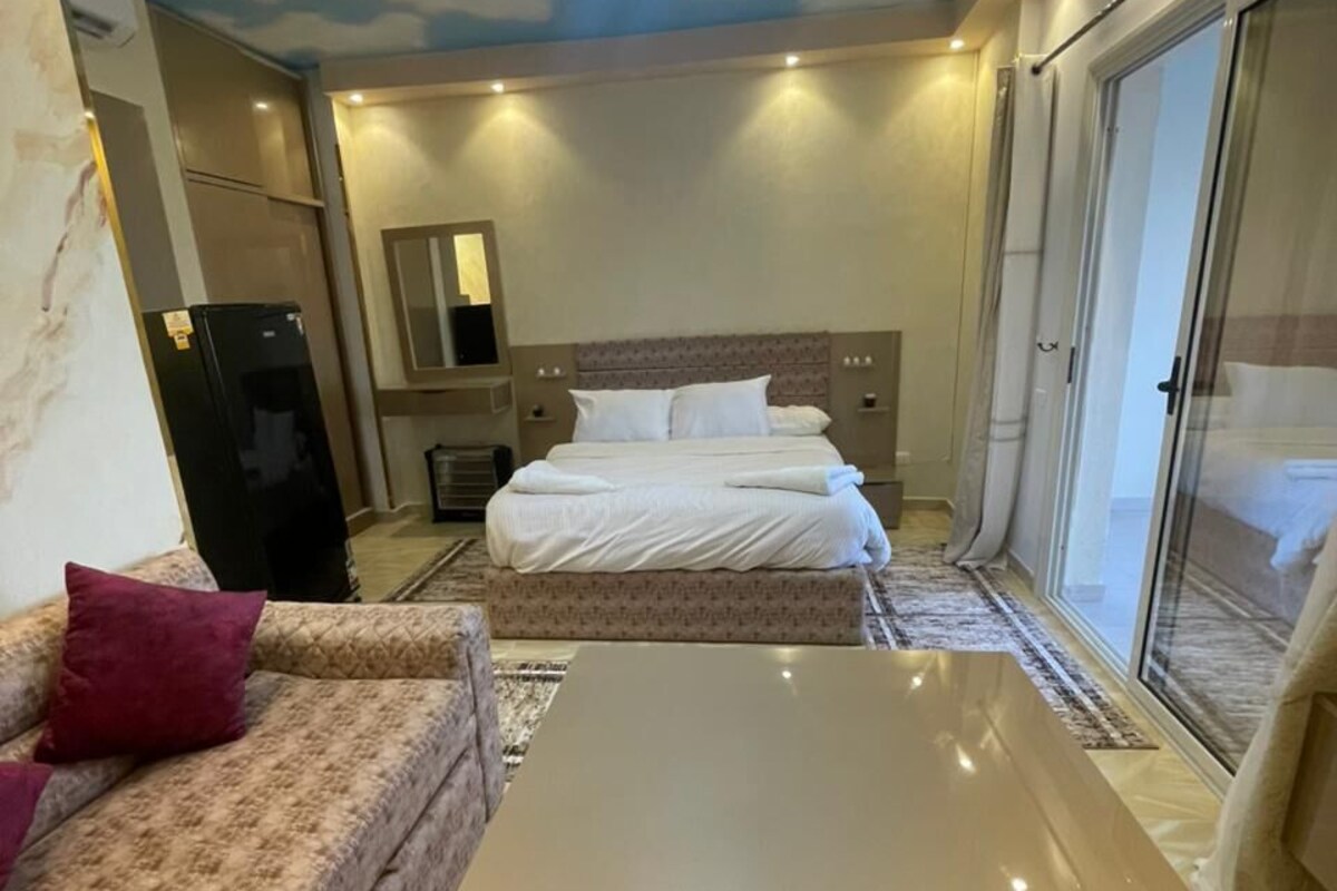 A hotel room with a bed, a sofa, a coffee table, and a ceiling with a cloud design.