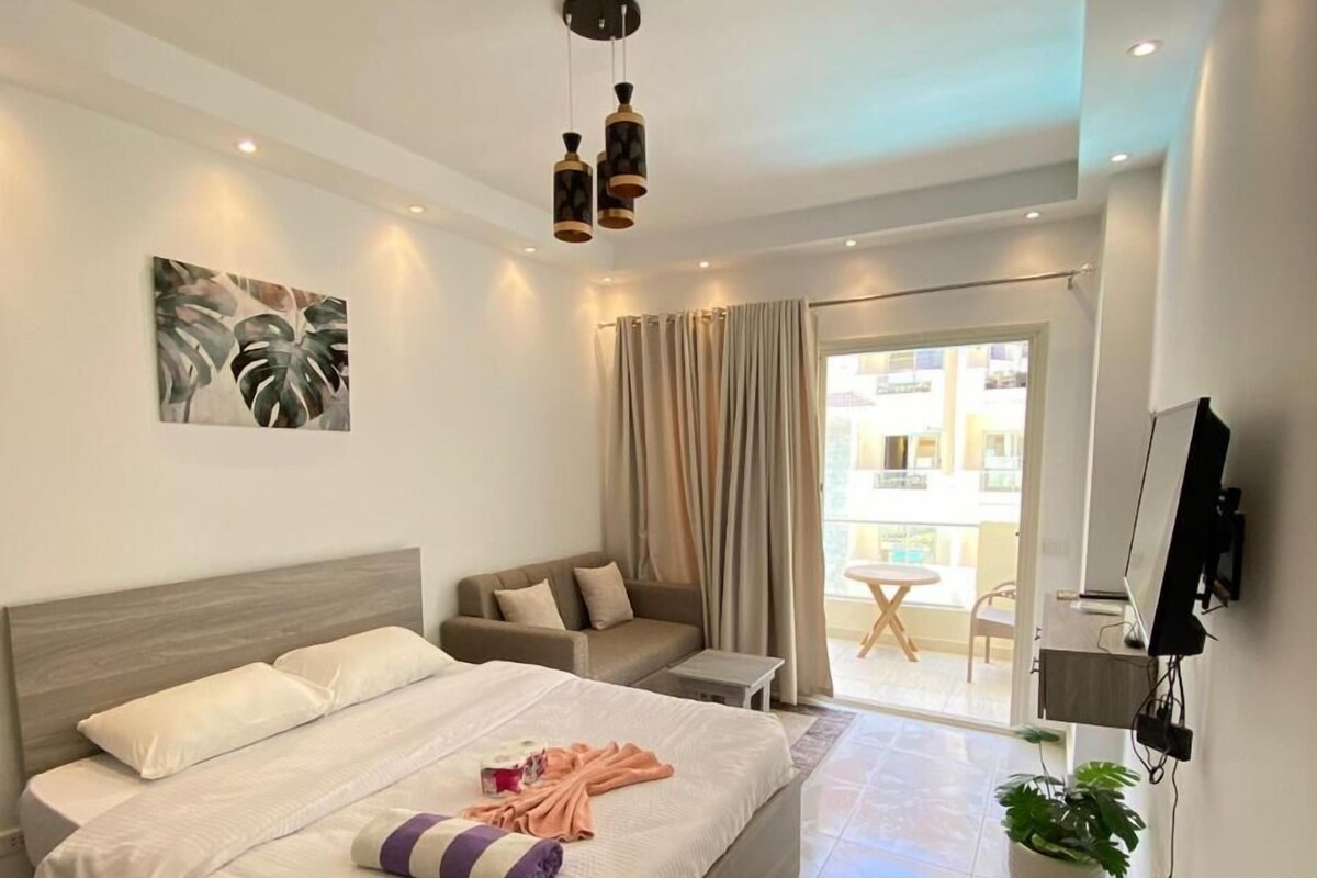 Una habitación de hotel moderna con una cama grande, un sofá, un televisor y un balcón con vistas.