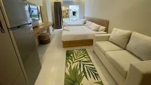 A modern hotel room with a bed, a sofa, a desk, and a refrigerator. - Florenza Khamsin Resort (Hurghada)