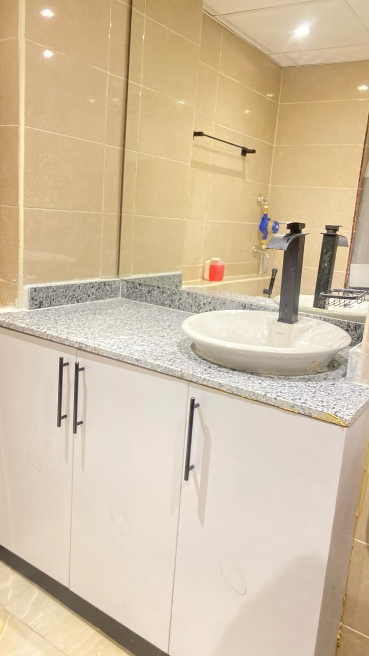 A bathroom with a white sink, a mirror, and beige tiles.