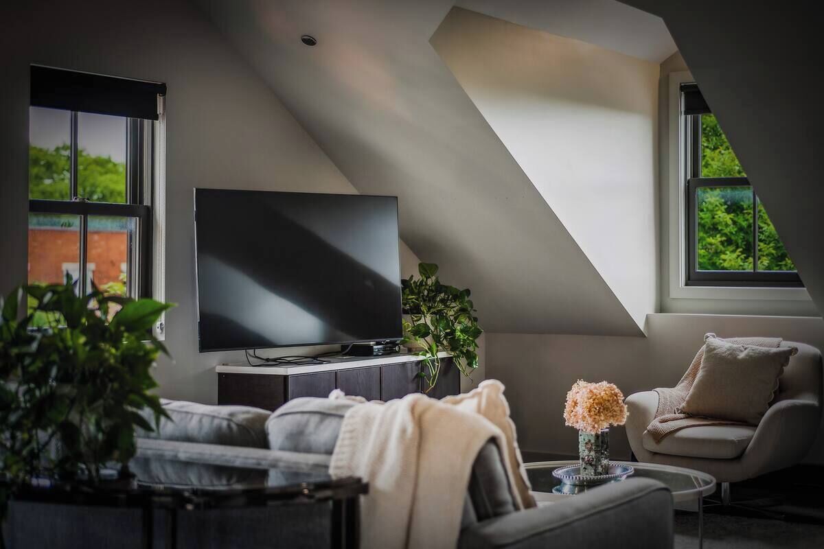 A modern living room with a flat-screen TV, a sofa, a chair, and a coffee table.