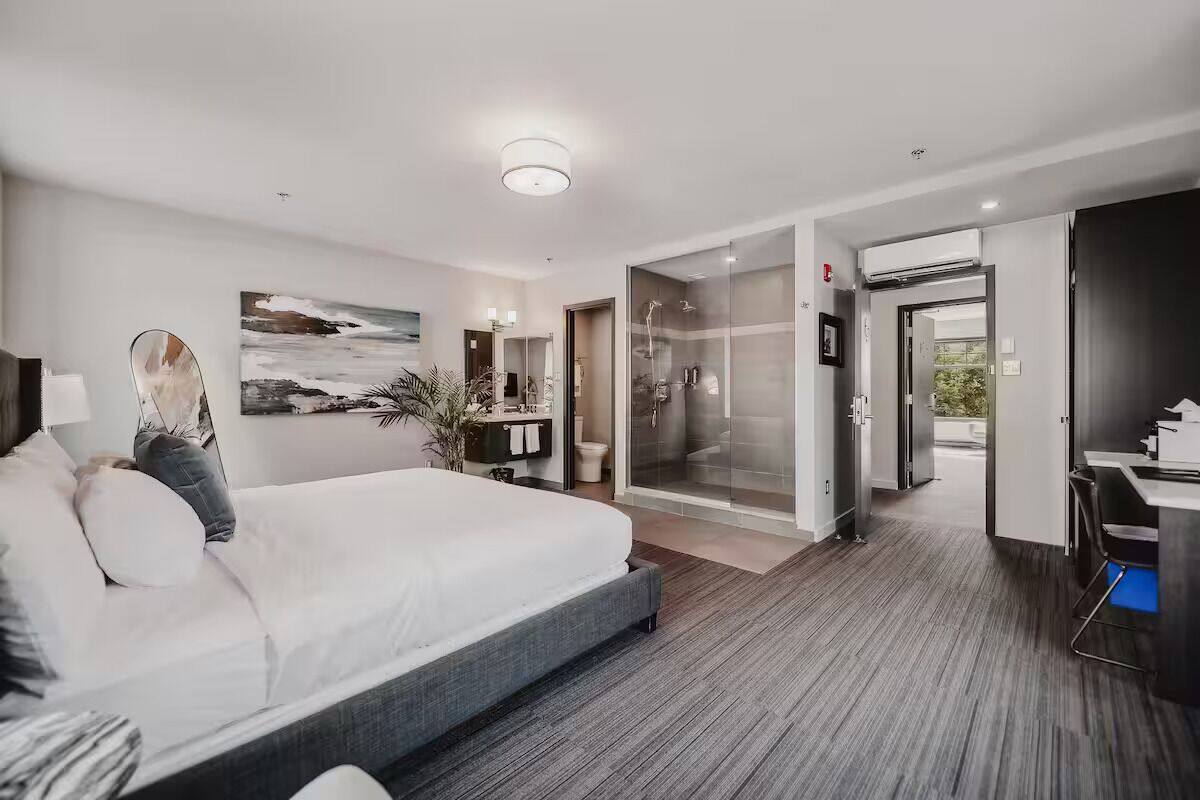 A modern hotel room with a large bed, a shower area, and a desk.