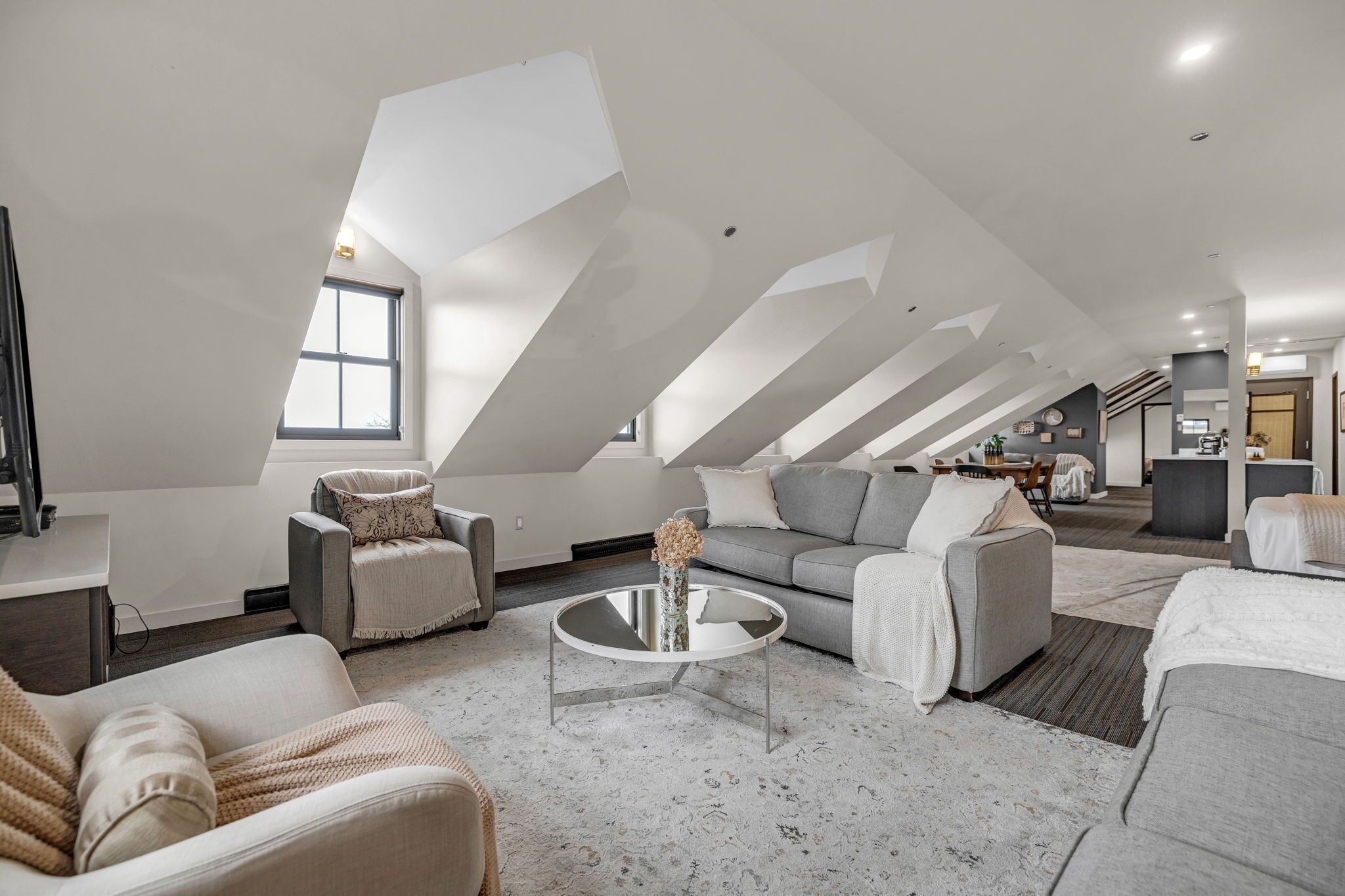 Un loft amplio con techos altos, un ventanal grande y una zona de estar moderna con sofás y una mesa de centro.
