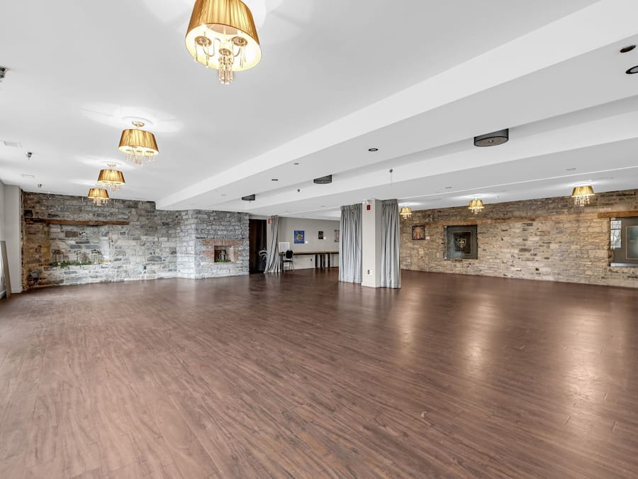 Une pièce spacieuse avec un mur en pierre, un plancher en bois et des lustres suspendus.