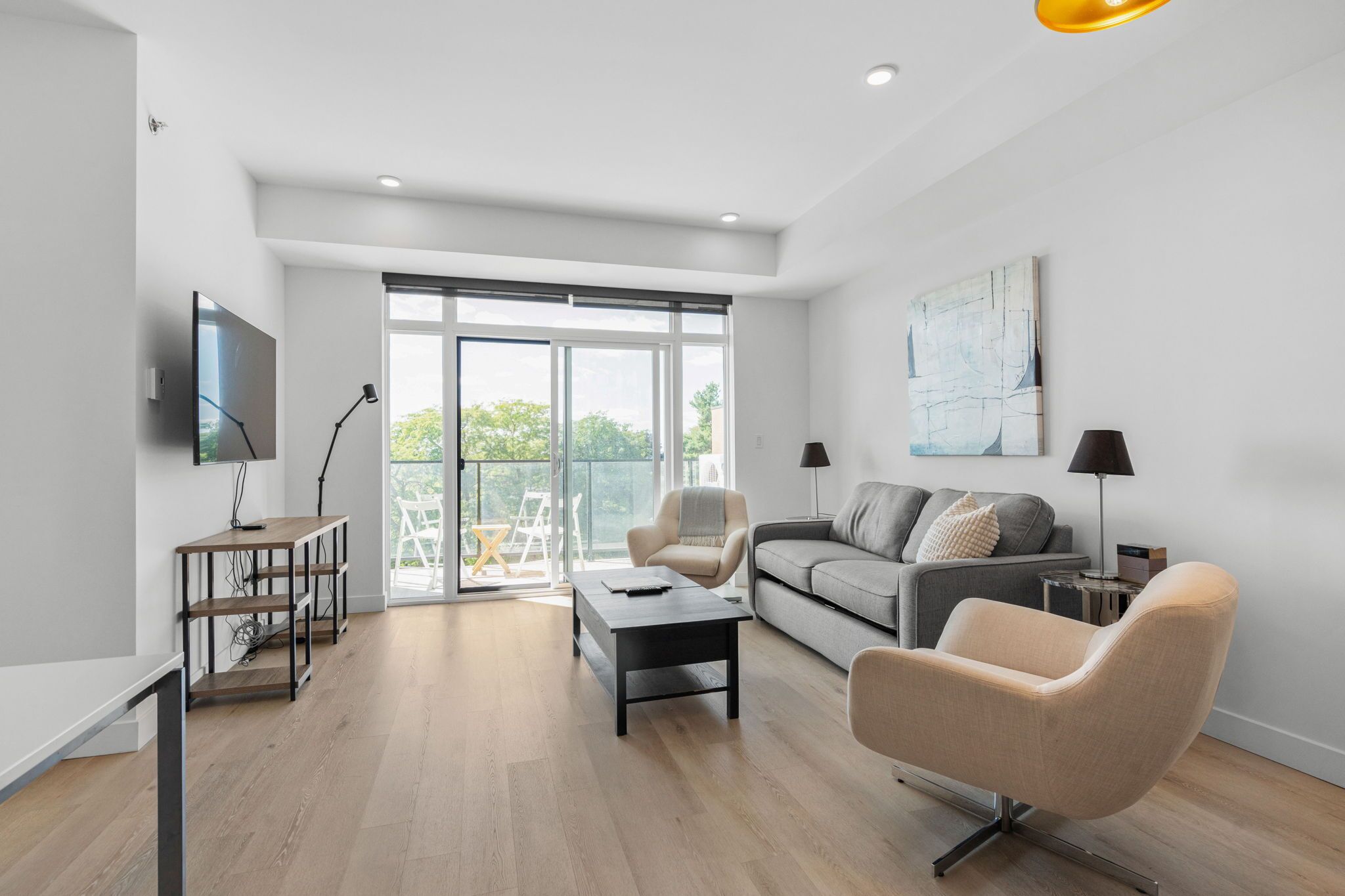 Una sala moderna con sofá, sillón, mesa de centro y televisor.