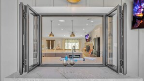 A modern kitchen with a large island, a built-in oven, and a stainless steel sink.