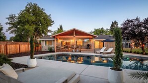 A house with a swimming pool, wooden deck, and outdoor seating area.