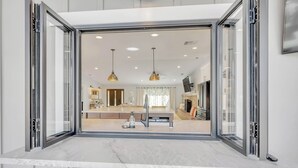 A modern kitchen with a large island, pendant lighting, and a view into the dining area.