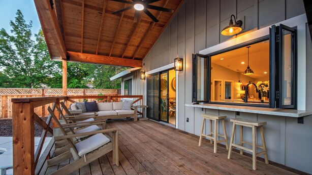 An outdoor deck with wooden furniture, a bar area, and a ceiling fan.