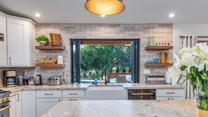 A modern kitchen with a marble countertop, built-in appliances, and a view of the outdoors.