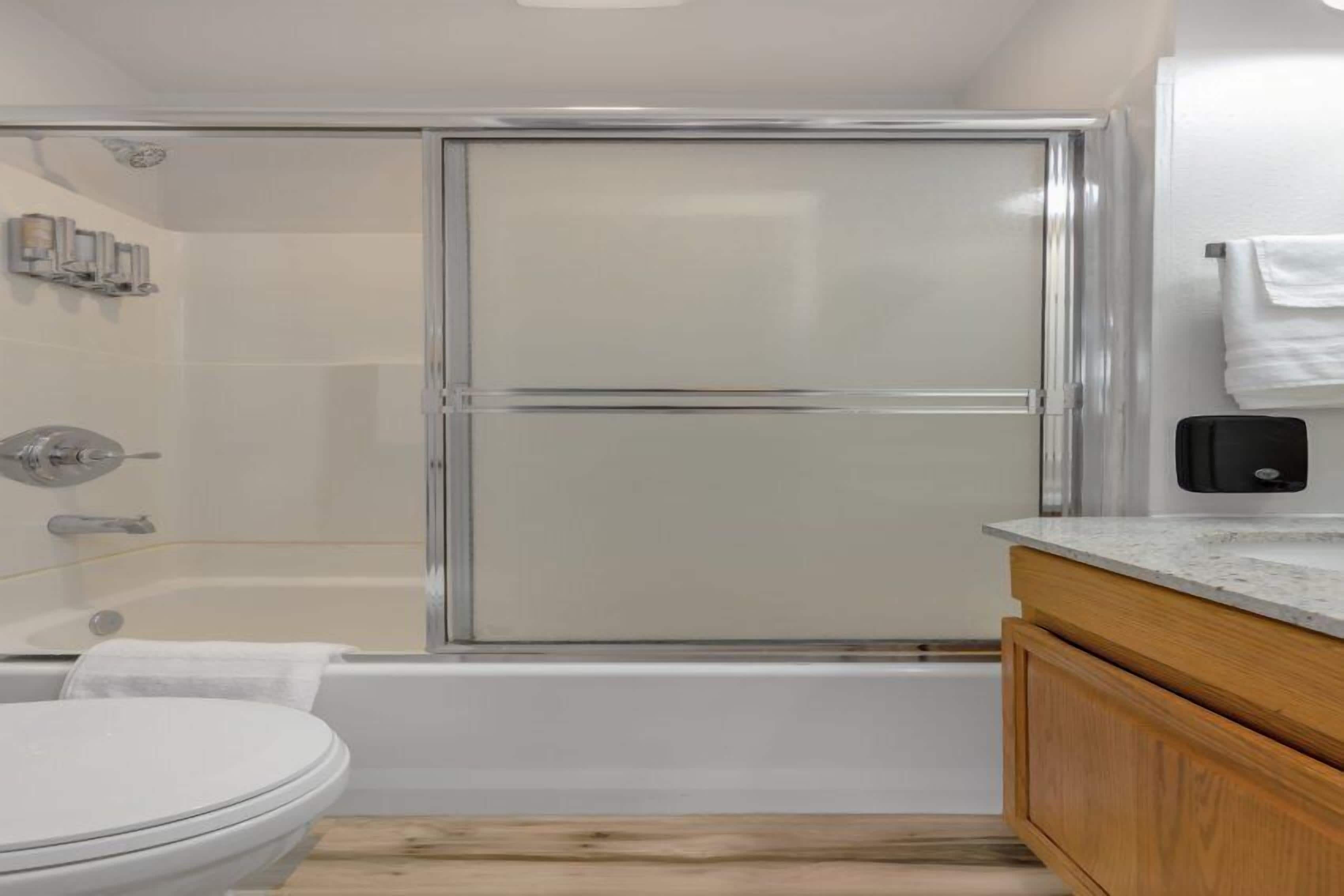 Een moderne badkamer met een douchecabine van glas, een wit toilet en houten kastjes.
