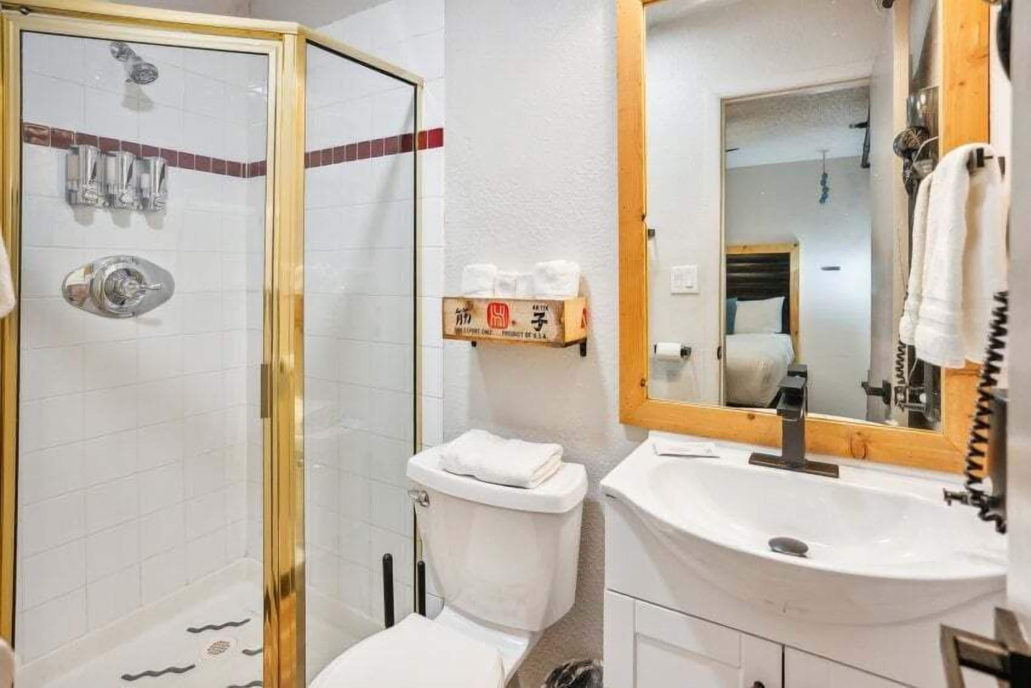 A bathroom with a glass-enclosed shower, a white sink, and a mirror above the sink.