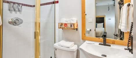 Un baño con ducha de vidrio, un lavamanos blanco y un espejo sobre él.