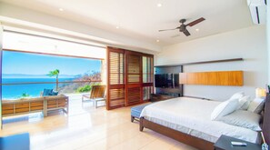 A bedroom with a large bed, a ceiling fan, and a view of the ocean. - Cruz de Huanacaxtle Arena Blanca 408 (La Cruz de Huanacaxtle)
