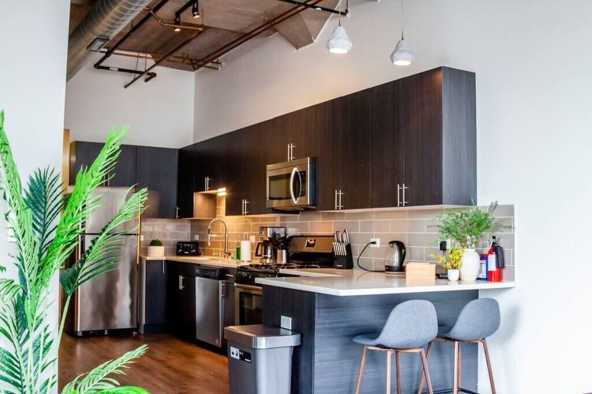 A modern kitchen with dark wood cabinets, stainless steel appliances, and a central island with bar stools.
