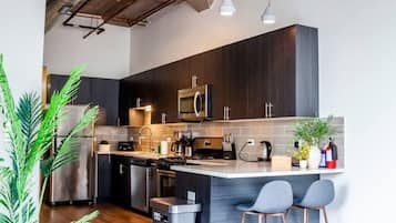 A modern kitchen with dark wood cabinets, stainless steel appliances, and a central island with bar stools.