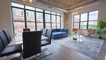 A modern office space with a large table, several chairs, a blue sofa, and a coffee table.
