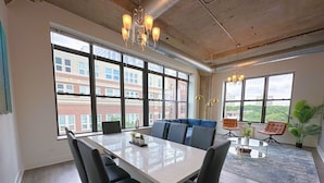 A modern meeting room with a large table, comfortable seating, and large windows offering views of the city. - Modern 3BR Corner Suite Near McCormick Place & Soldier Field that Sleeps 10 (Chicago)