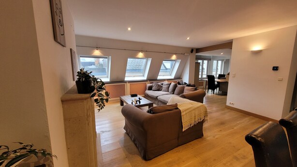A modern living room with a sofa, coffee table, and a view of the street through large windows. - Spacious 3BR apartment with rooftop terrace (Antwerpen)