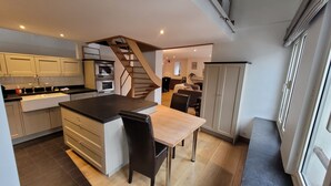 A modern kitchen with a central island, built-in appliances, and a staircase leading to another level. - Spacious 3BR apartment with rooftop terrace (Antwerpen)