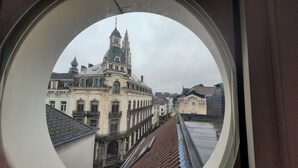 A view through a window of a building with a prominent tower and multiple windows. - Spacious 3BR apartment with rooftop terrace (Antwerpen)