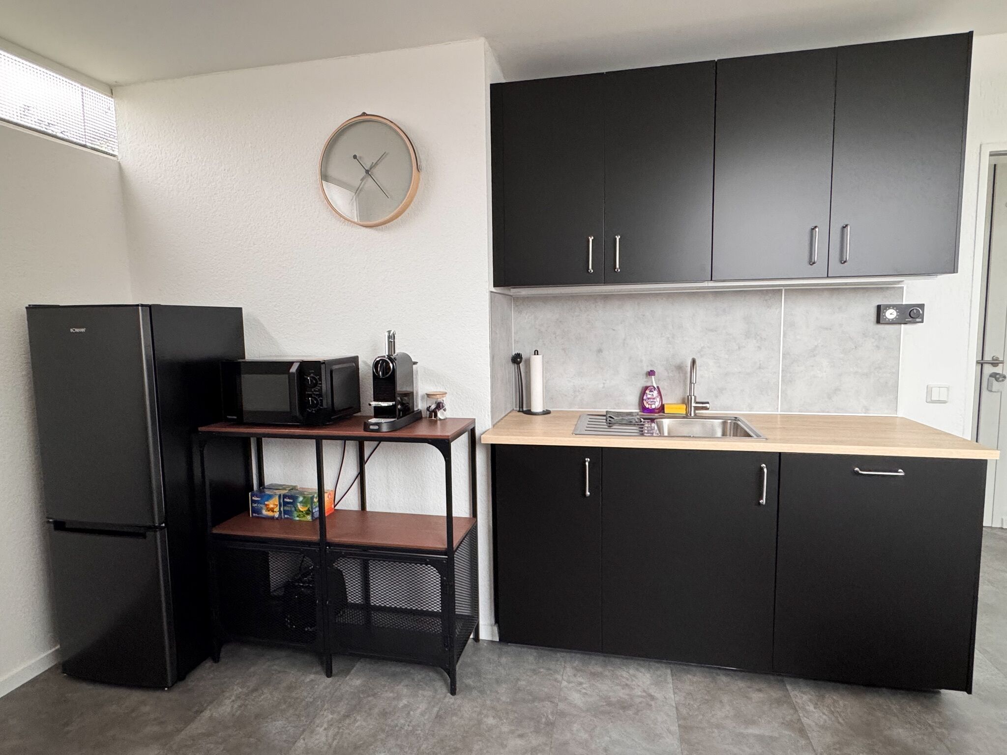 A compact kitchen with black cabinets, a microwave, a coffee maker, and a sink.