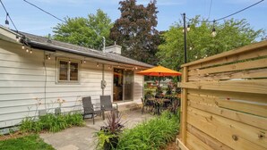 Una casa con un patio, mobili da esterno e una recinzione in legno.