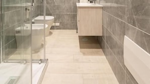 A modern bathroom with a glass shower enclosure, a toilet, and a vanity with a mirror. - Dimora Cinque Santi (Naples)
