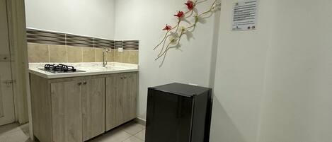 A kitchen with a gas stove, sink, and a black refrigerator.