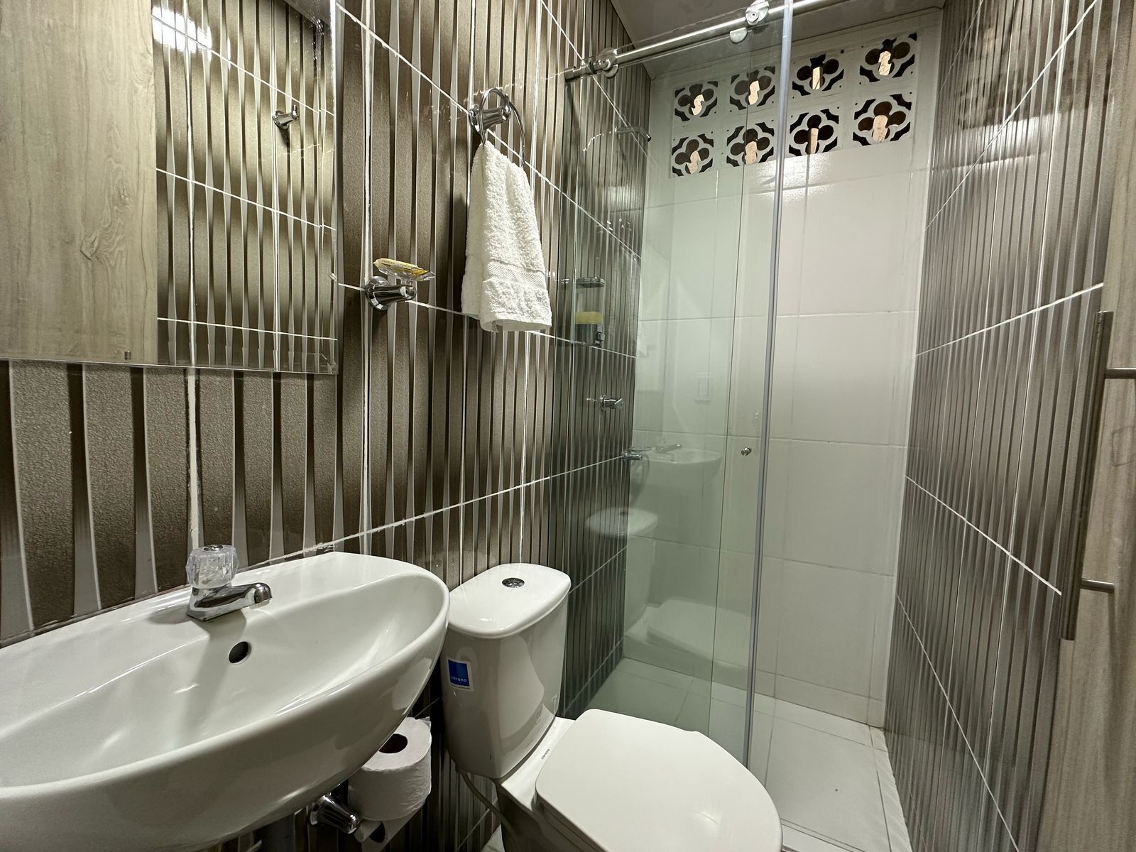 A bathroom with a sink, toilet, and glass shower enclosure.