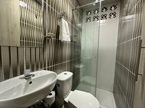 A bathroom with a sink, toilet, and glass shower enclosure. - Hospedarte Cali (Cali)