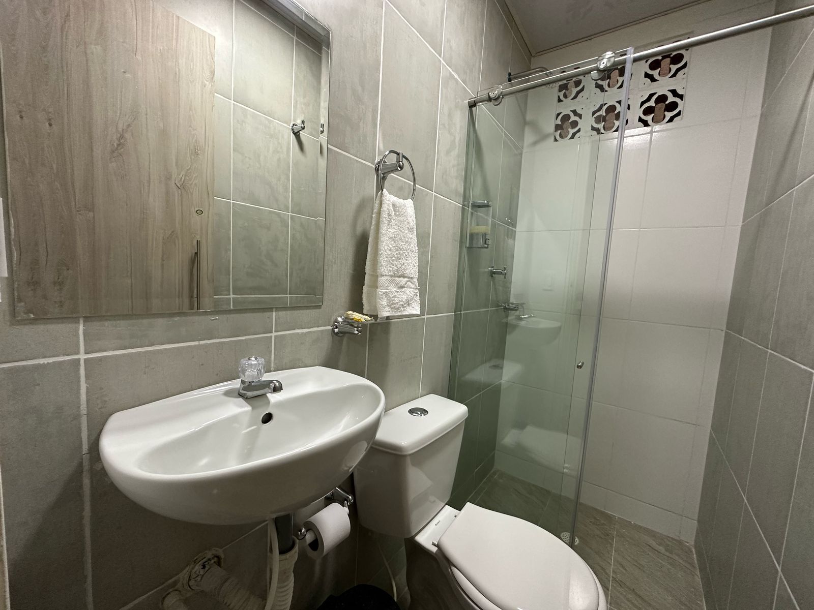 A bathroom with a sink, toilet, and glass shower enclosure.