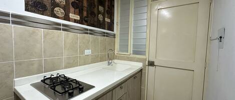 A kitchen with a gas stove, a sink, and wooden cabinets.
