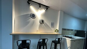 Μια μοντέρνα κουζίνα με μια κεντρική νησίδα, τρία σκαμπό μπαρ και φωτιστικά οροφής.