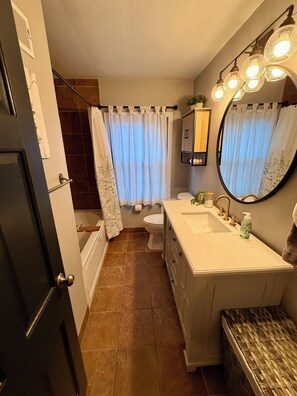 Une salle de bain équipée d’une baignoire, de toilettes, d’un lavabo et d’un miroir.