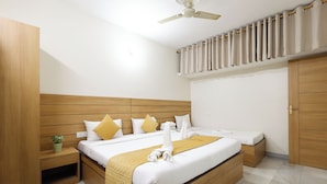 A hotel room with a large bed, wooden headboard, a ceiling fan, a bedside table with a plant, and a wardrobe. - BALAJI HOMESTAY VARANASI (Varanasi)