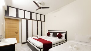 A hotel room with a bed, a desk, a wardrobe, and a ceiling fan. - BALAJI HOMESTAY VARANASI (Varanasi)